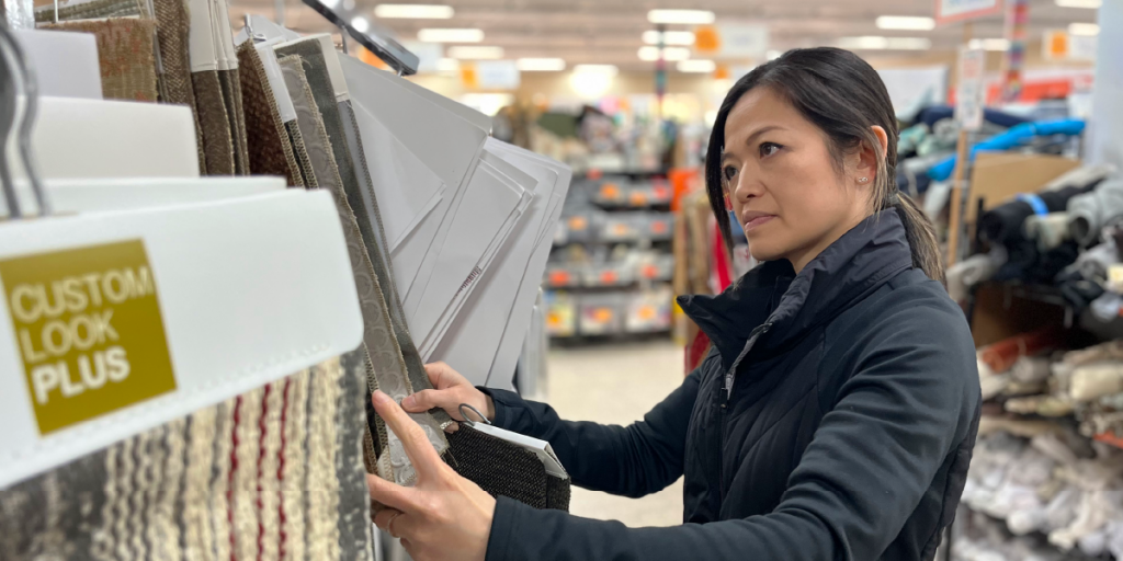 Aileen flips through hanging architectural fabric samples.