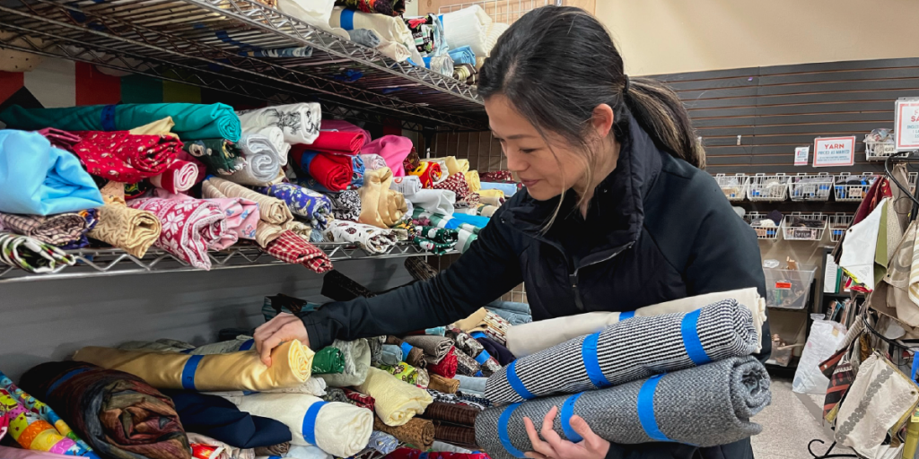 Aileen searches through fabric rolls at Austin Creative Reuse.