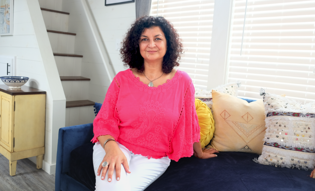 Amal sitting on a couch with colorful pillows around her.