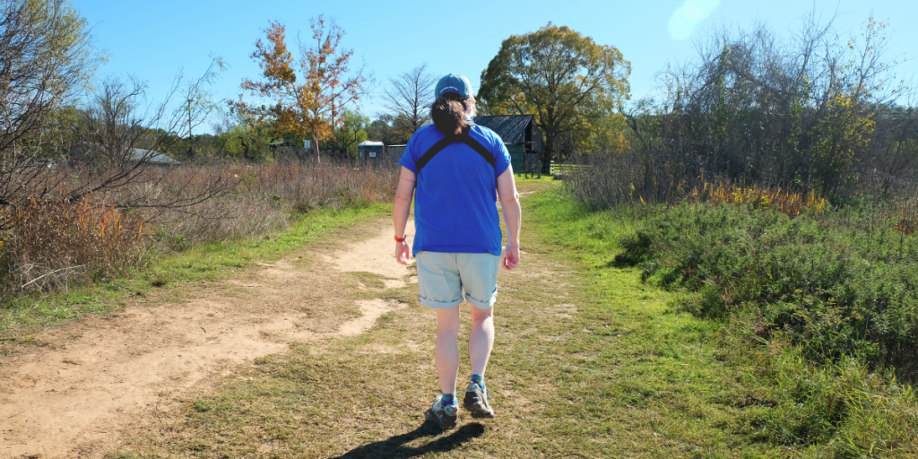 Amy walks away from the camera down a path at Commons Ford Ranch.