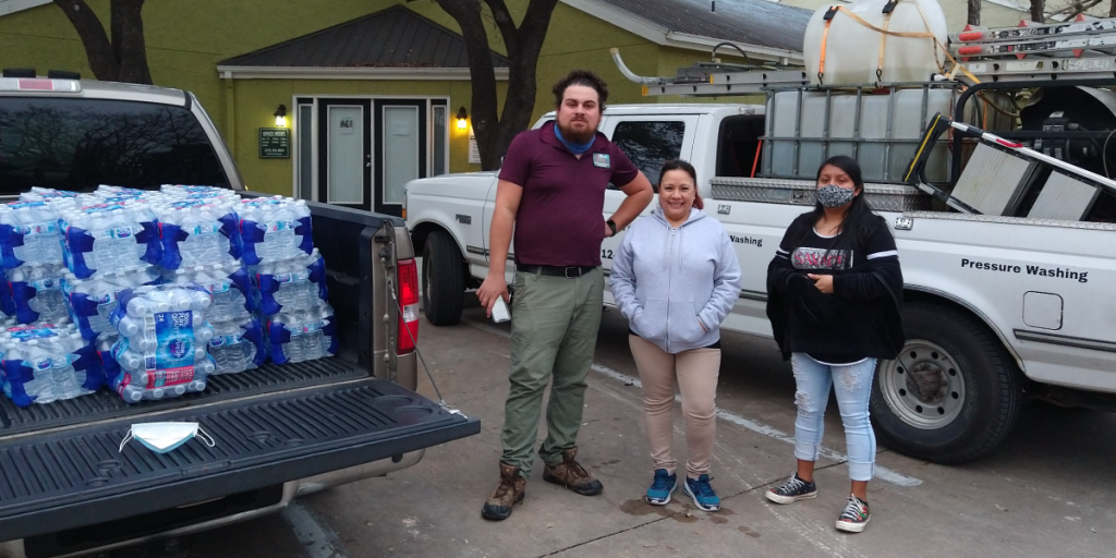 Frances stands outside with two other people next to a pickup truck loaded with bottled water.