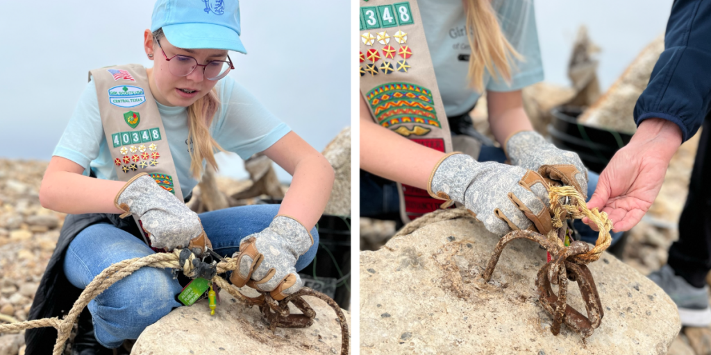 Eleanor works on cutting old, frayed rope from a rock on the shoreline.