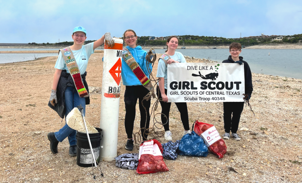 Scouts pose in front of Lake Travis with the trash they collected.