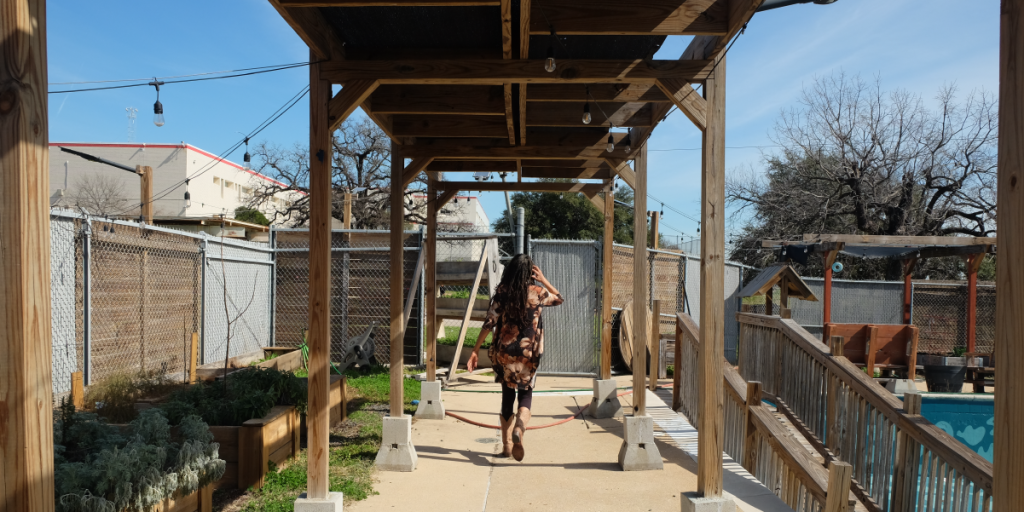 Harvé walks away from the camera through a covered shade structure.