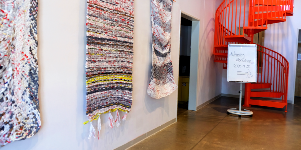 The lobby of the UpFront Gallery with three woven mats hanging against the wall.