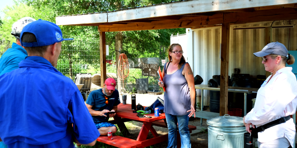 Leatha talks in a circle of people with a clipboard in her hand.