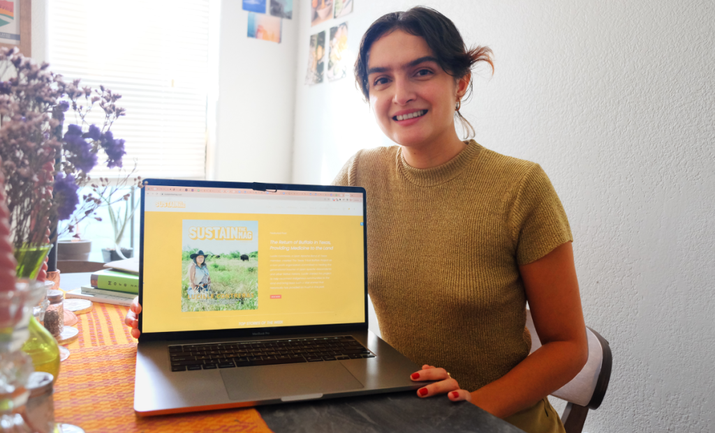 Reza holds her laptop showing the homepage of the SUSTAIN THE MAG website.