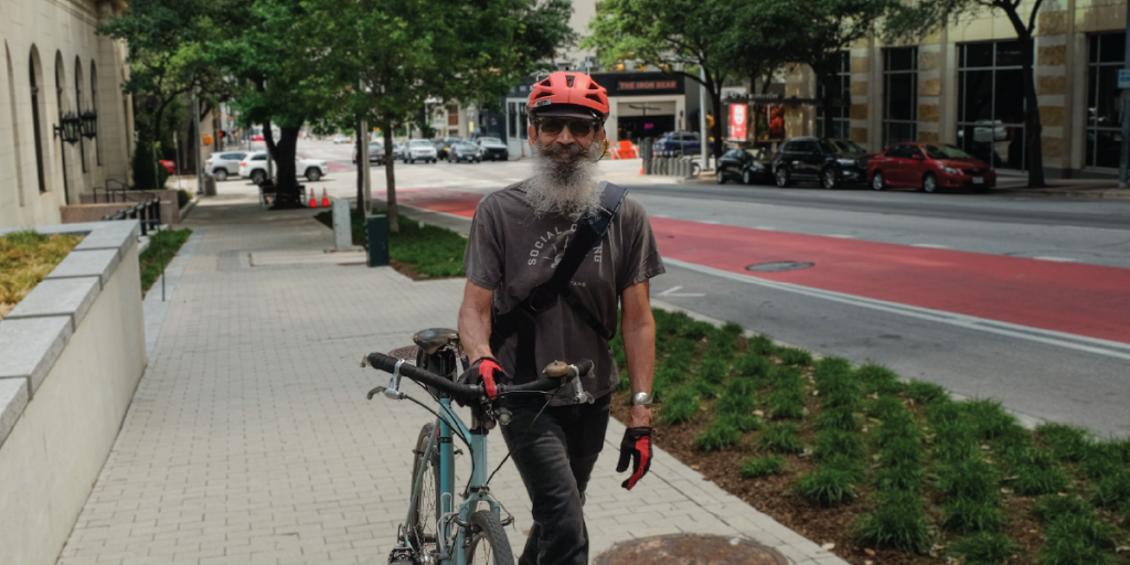 Ricardo walks with his bike near his workplace in downtown Austin.