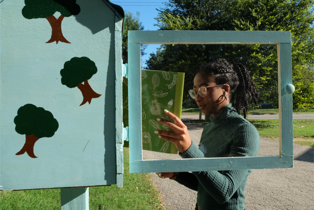 A photo of Sheridan placing items in the completed free little library.