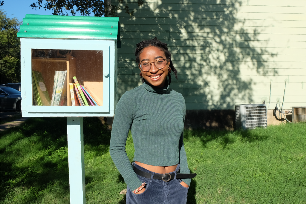 A photo of Sheridan standing in front of her completed free little library.