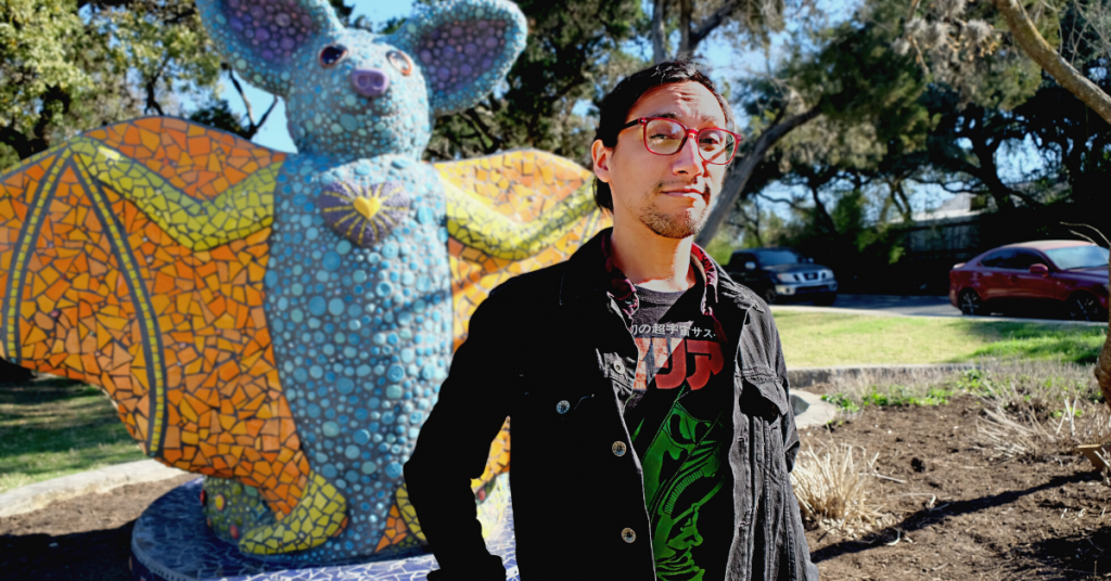A photo of Sergio at Ricky Guerrero Park in front of a mosaic bat sculpture.
