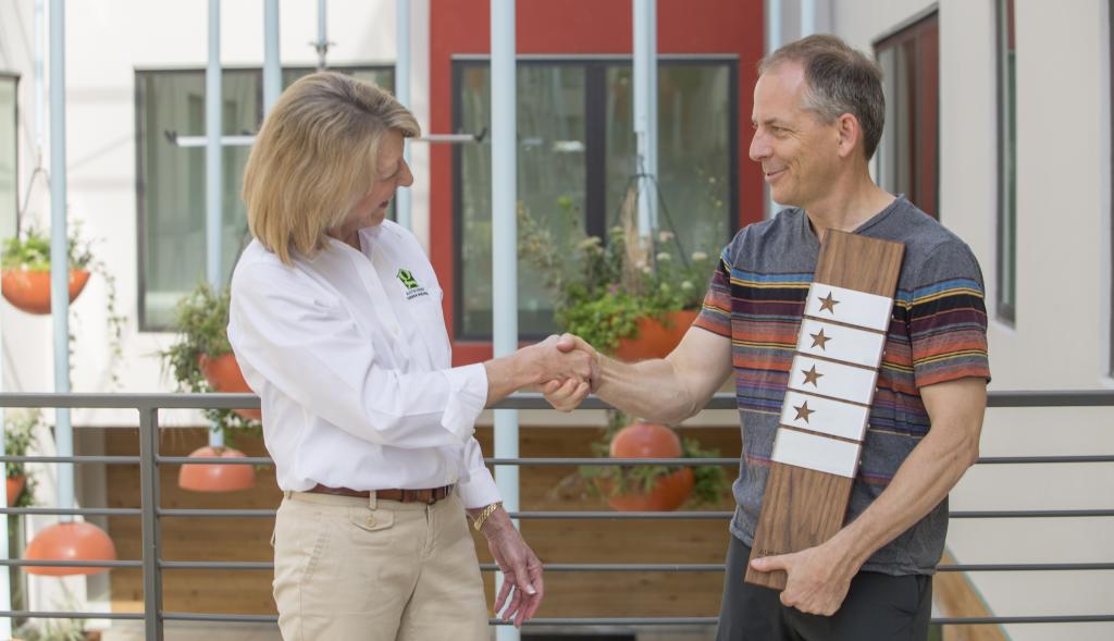 Walter Moreau accepting a four-star award and shaking hands with Austin Energy's Debbie Kimberly.