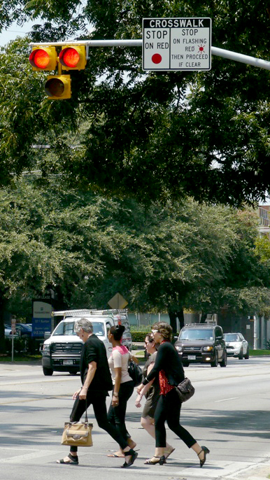 Pedestrians cross the street after activating a pedestrian signal.