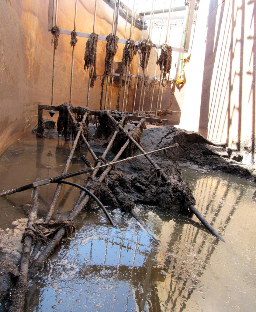 Large amount of accumulated grit, flushable wipes, and rags in a wastewater treatment basin. The grit is comprised of sand, gravel, plastic, and other inorganic material flushed into the wastewater system. The weight of the flushable wipes has caused some of the City's aeration equipment to break.
