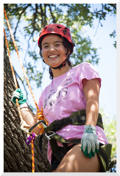 Esme using safety gear and rope to climb in a live oak tree in Austin, Texas
