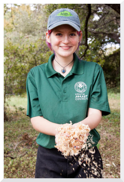 Lydian holding a double handful of sawdust in the outdoors