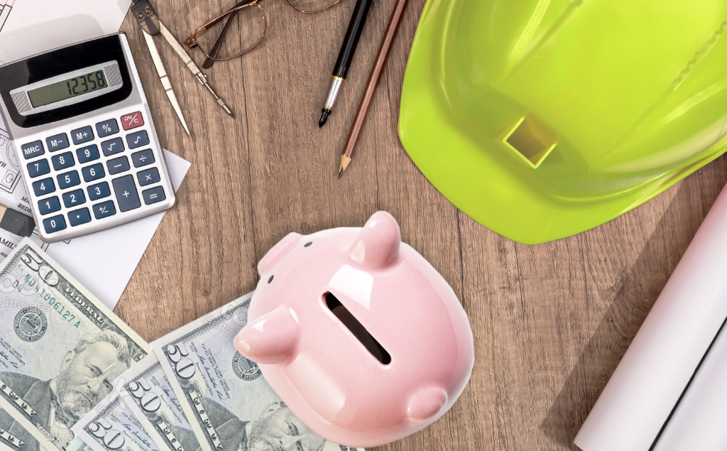 hard hat, piggy bank, paper money, calculator, pencil, reading glasses on table.