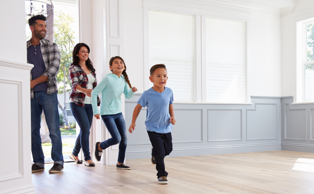 Family of four running through the door of a house