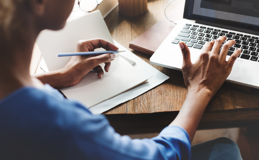 woman working on a laptop taking notes