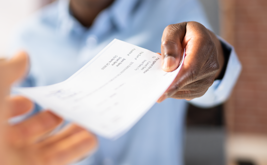 person handing a paper check to another person