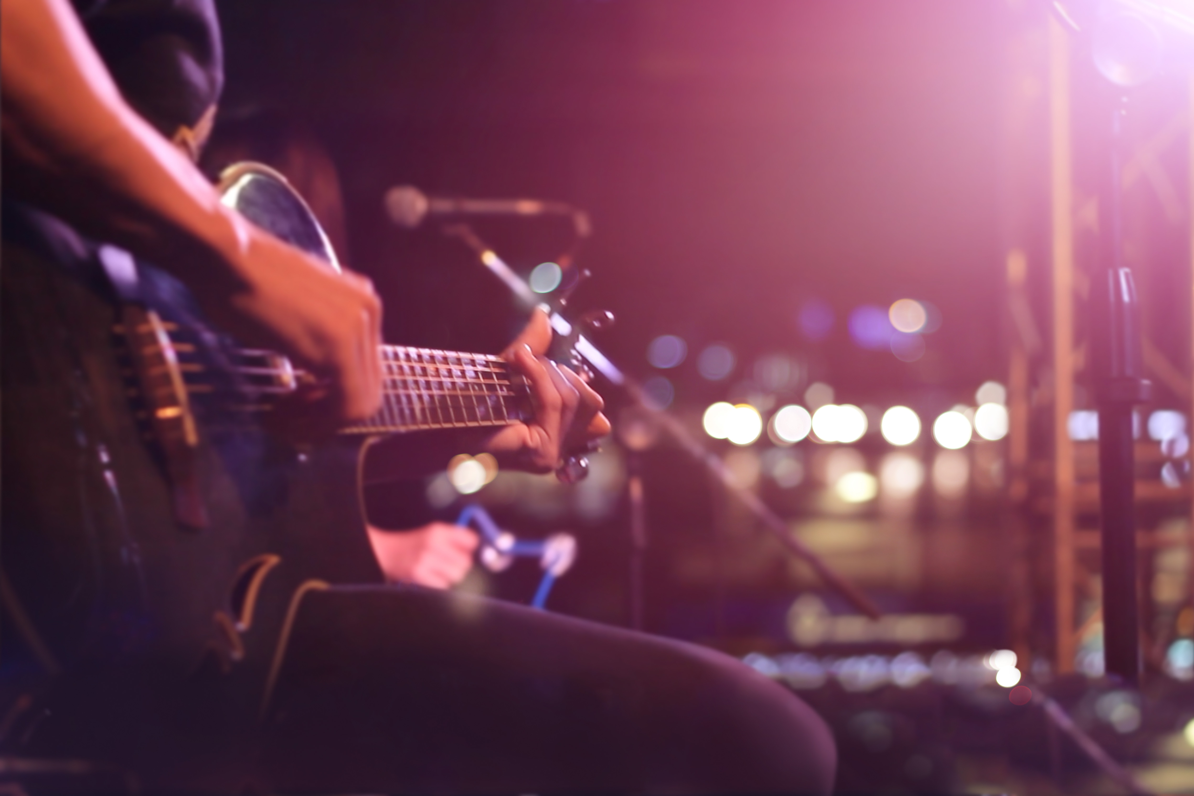 Creative Space Assistance Program Person playing guitar with bright stage lights behind