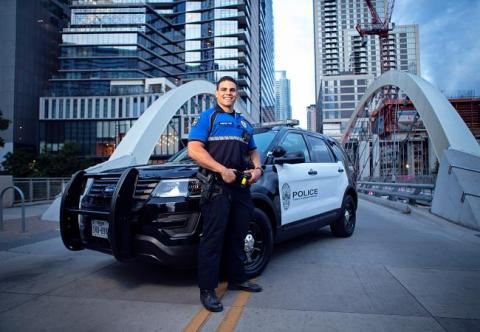 Officer posing in front of patrol car on a downtown bridge