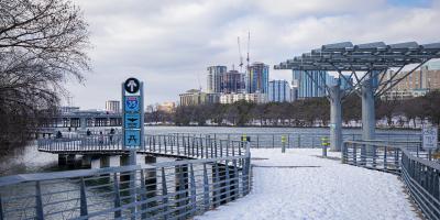Snowfall on Ladybird Lake riverwalk with Austin skyline in the background