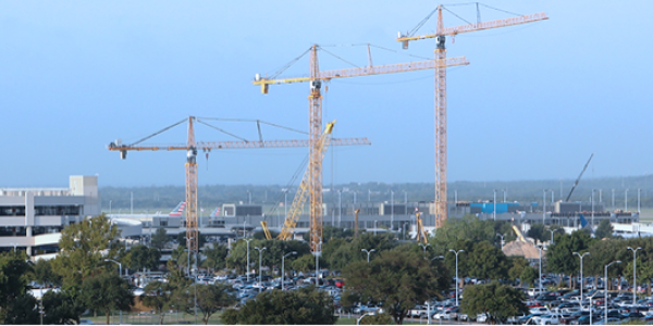Construction cranes line the skyline near the airport. The cranes are constructing the now completed airport parking garages.