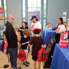 A family receives information about emergency preparedness from city staff at fair booth.