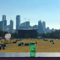 A photo showing an Austin HSEM water bottle in front of the ACL festival with the Austin skyline in the background.