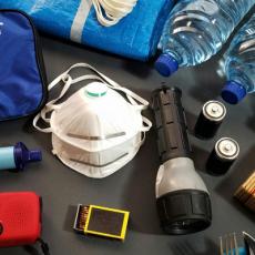 A photo showing preparedness kit items including a first aid kit, N-95 masks, bottled water, flashlight, water filter, and other items.