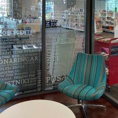 Library sitting room with multiple language etched glass wall looking out into room with bookcases