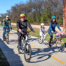 photo of people bicycling on a trail next to a railroad track