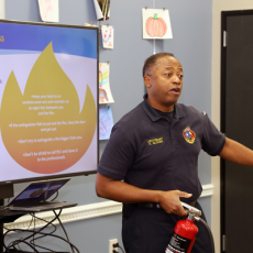 A photo showing an Austin firefighter demonstrating how to use a fire extinguisher at a classroom training for the community.