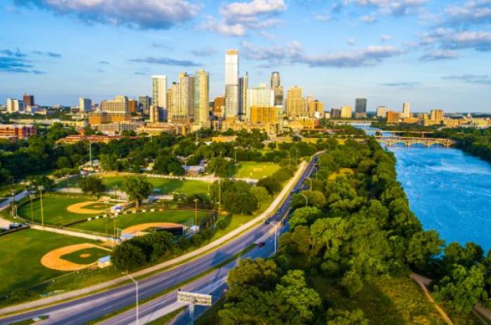 Austin cityscape with blue river in right side of image and skyscrapers in back and green park to left
