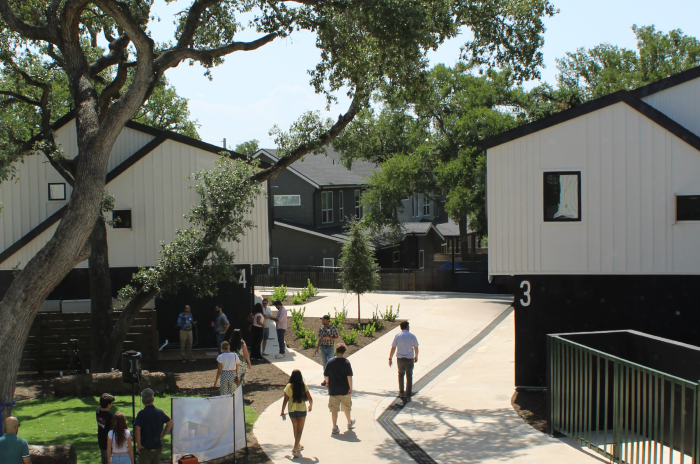 Image shows view of  Industry SOMA townhomes and grounds from an upstairs window of a three bedroom unit. Below people can be seen walking the ground and talking under the shade of trees.