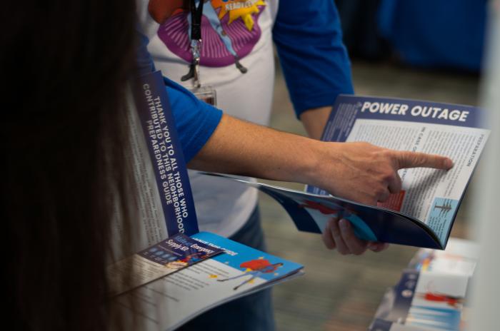 photo of a hand pointing to preparedness information regarding power outages in a booklet